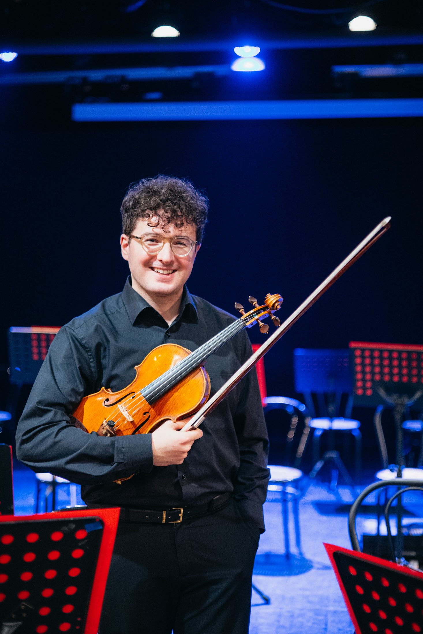 Un giovane violinista dell’ensemble sorride con il suo violino e l’archetto