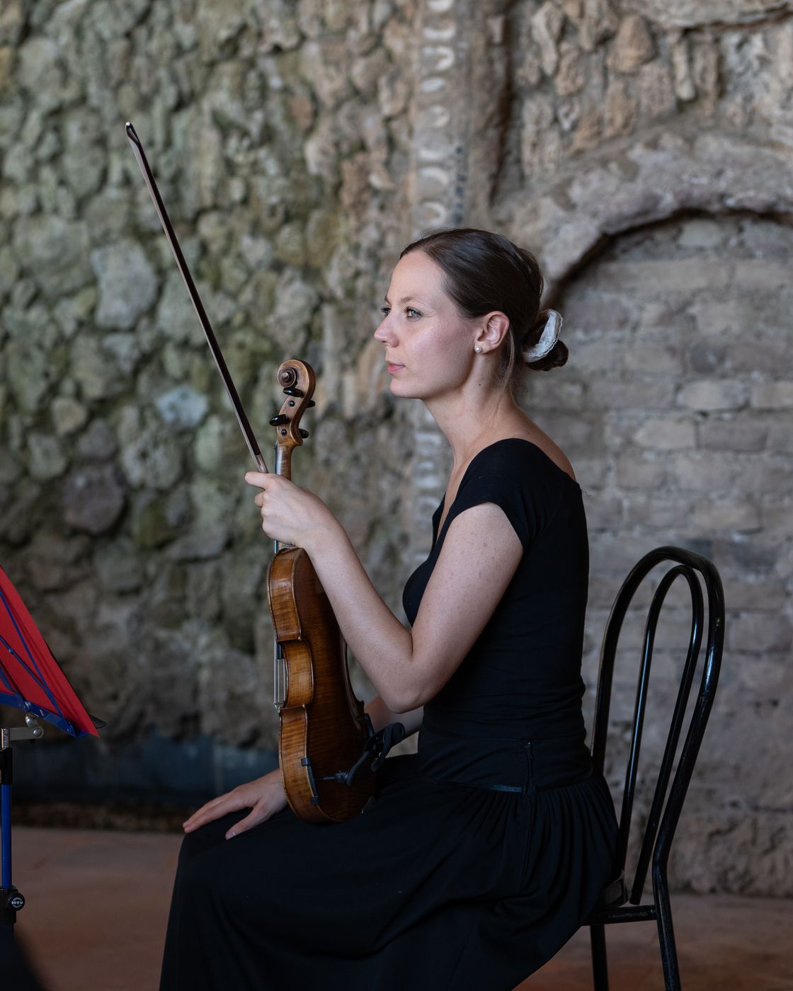 Una violinista dell’ensemble seduta in una sala di pietra