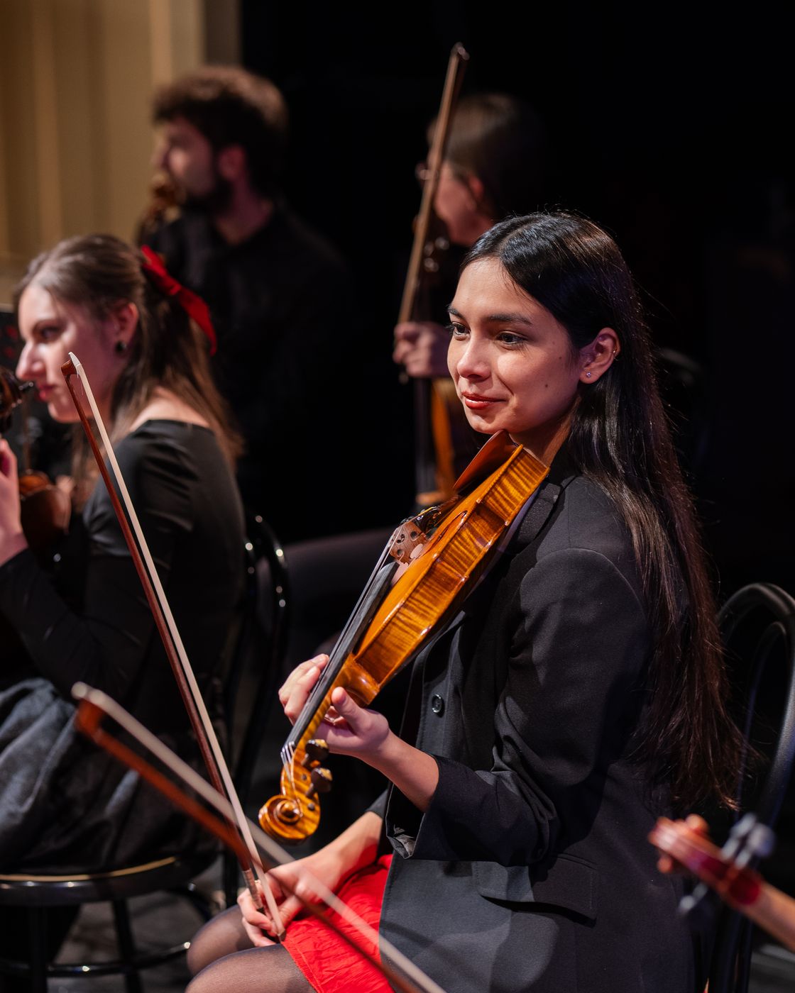 Una violinista dell’ensemble suona in orchestra